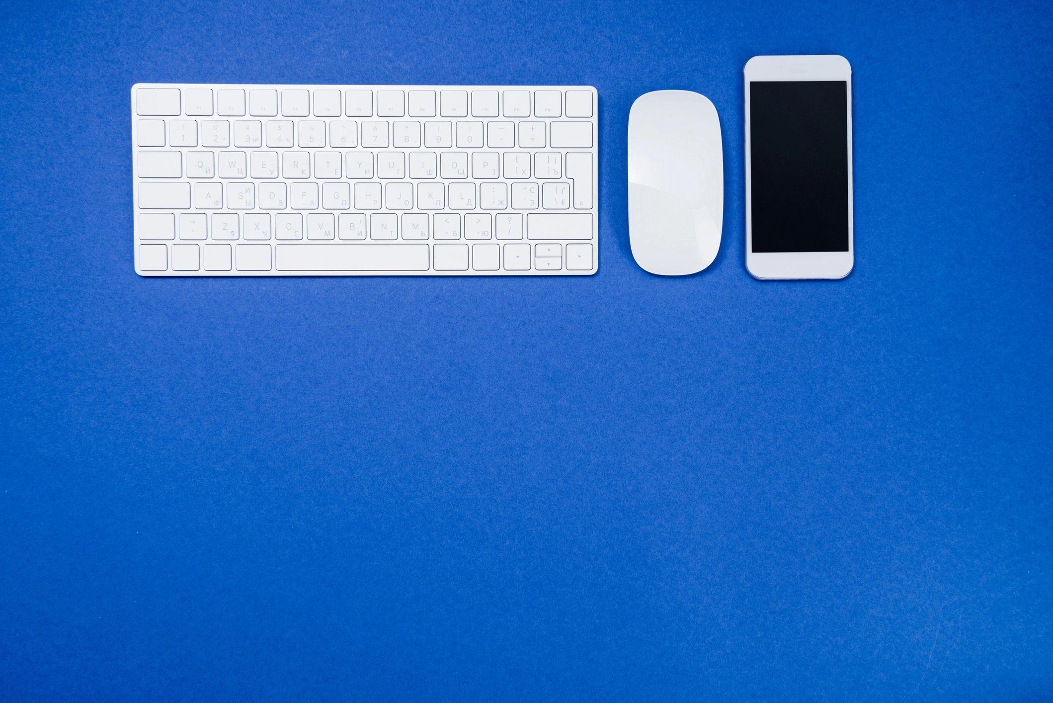 Blue desk with smartphone keyboard and mouse